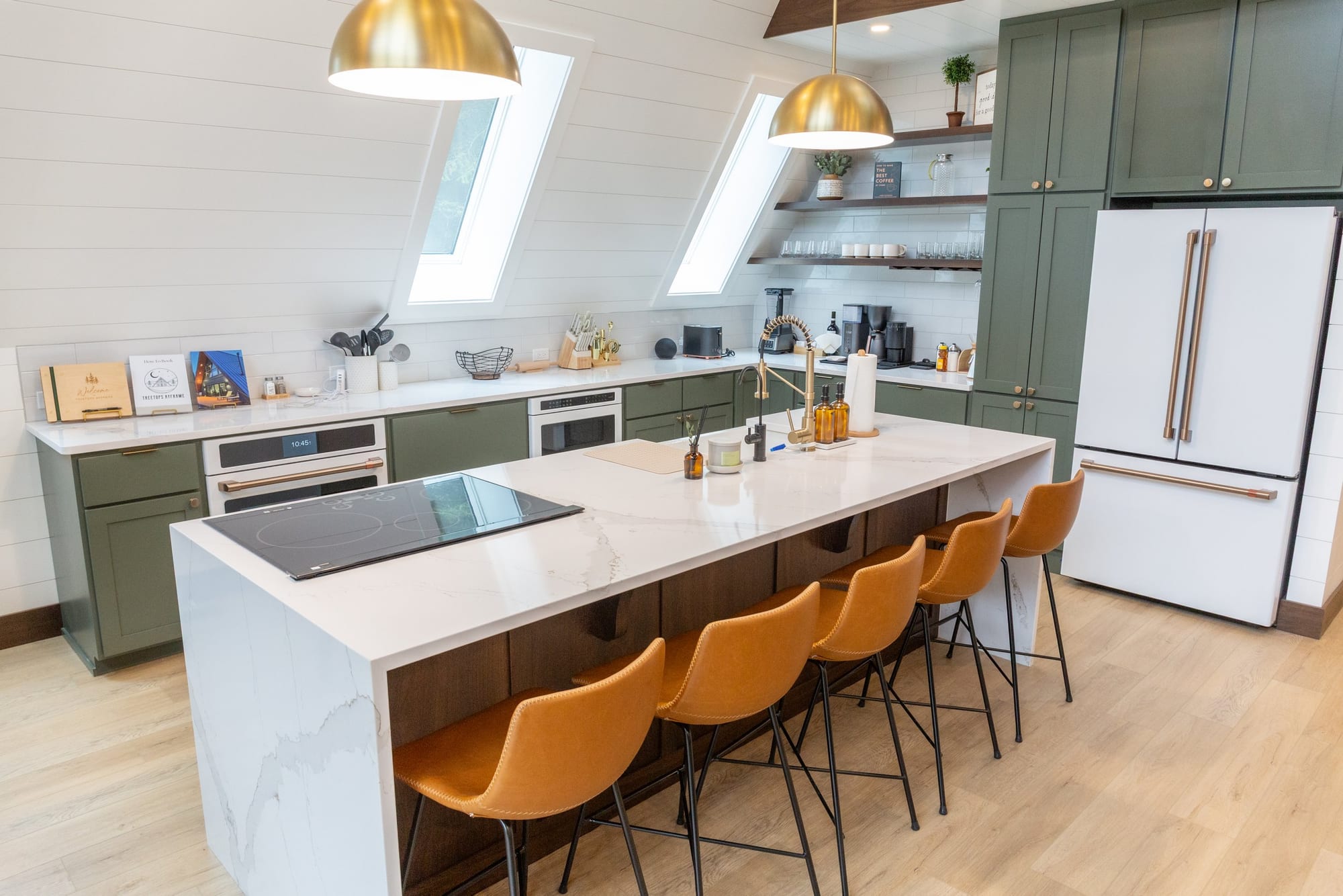 Kitchen island with brass pendants and green cabinetry