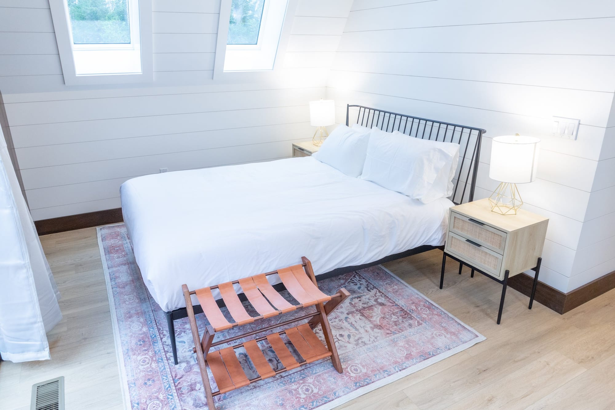 A bedroom suite with a made bed and wood floors